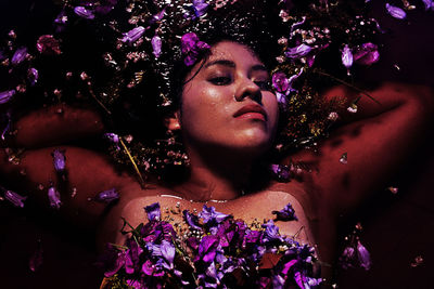 Portrait of shirtless young woman with purple flowers in water