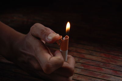 Cropped hand holding illuminated cigarette lighter