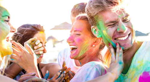 Close-up of friends celebrating holi with powder paint at beach