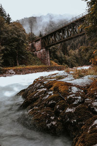 Bridge over river against sky during winter