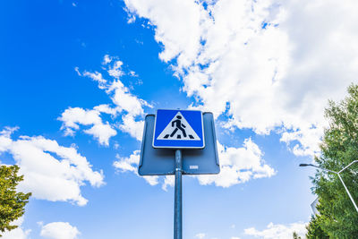 Blue and white pedestrian crossing sign on the sky background