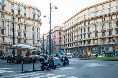 Motorcycles parked on road by buildings in city