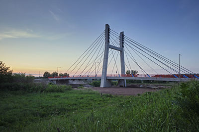Bridge over field against sky during sunset