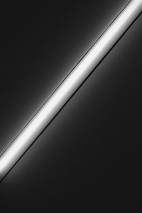 Low angle view of illuminated lighting equipment against wall