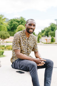 Positive afro american stylish man in european city with electronic device