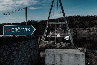 Information sign on riverbank against sky