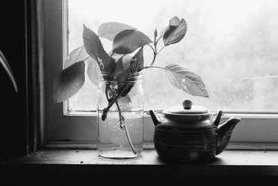 Close-up of teapot by vase on window sill