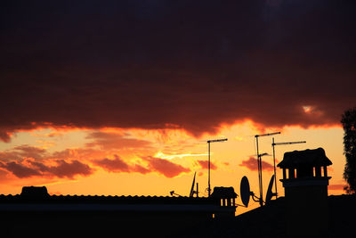 Silhouette people on land against dramatic sky during sunset