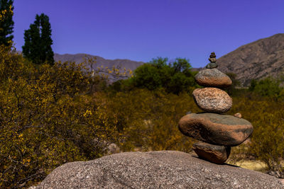 Stack of pebbles on rocks against clear sky