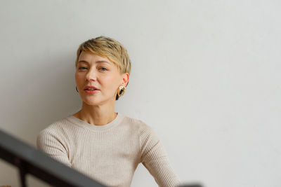 Portrait of young woman standing against wall