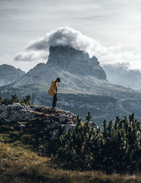 Full length of man standing on rock by mountain against sky