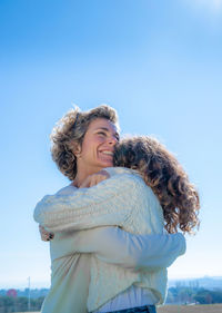 Closeup portrait of smiling mother embracing daughter on sunny day