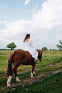 Young woman riding horse on field