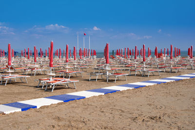 Row of chairs on beach against blue sky