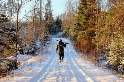 Rear view of man walking on snow covered road