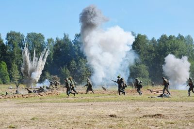 Army soldiers running by explosion on field