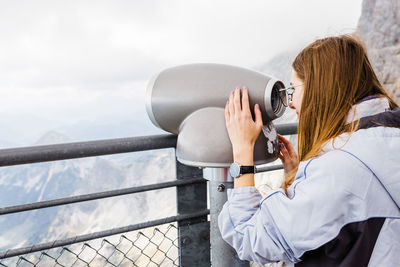 Young women looks at mountain views in binoculars from observation