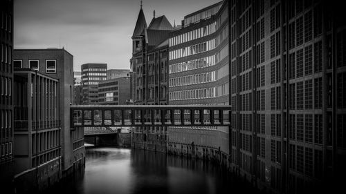 Bridge over canal amidst buildings in city against sky