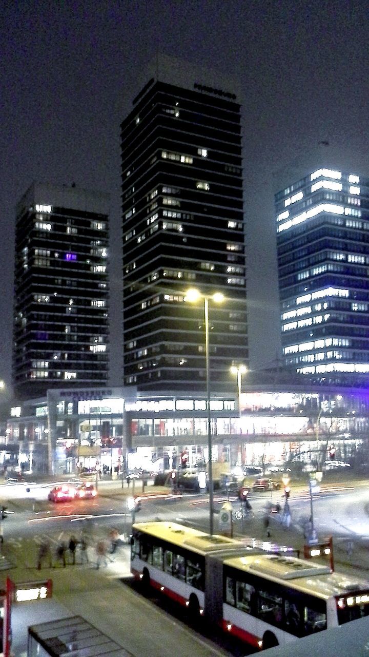 building exterior, architecture, built structure, city, transportation, illuminated, car, skyscraper, modern, office building, night, street, land vehicle, city life, mode of transport, tall - high, road, building, traffic, city street