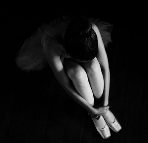 High angle view of ballet dancer sitting over black background