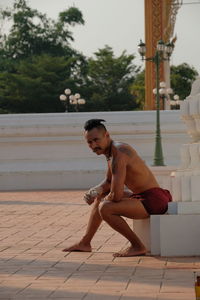 Portrait of shirtless man sitting outdoors