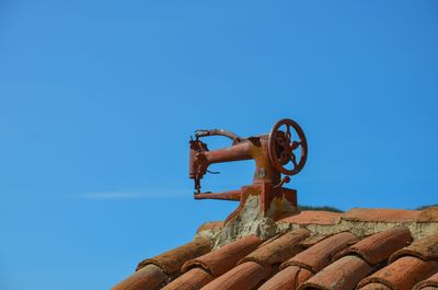 Low angle view of rusty roof against clear blue sky