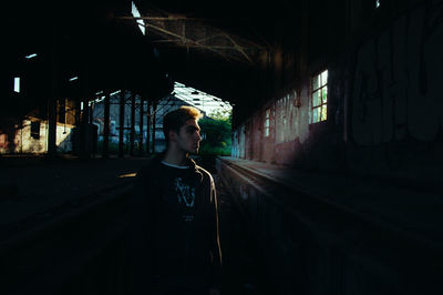 Thoughtful teenage boy standing in abandoned railroad station