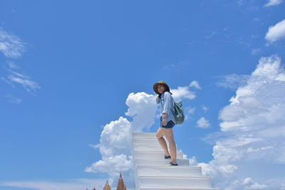 Low angle view of woman standing against blue sky