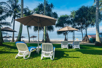 Chairs and tables on beach against sky