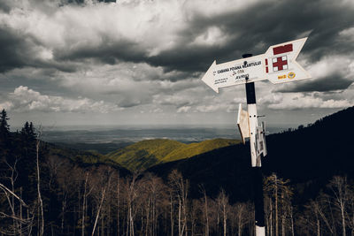 Low angle view of sign board on mountain against sky