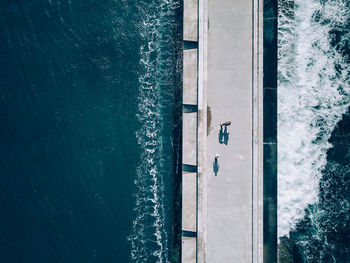 High angle view of people walking on pier over sea during sunny day