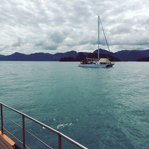 Boats sailing in sea against cloudy sky