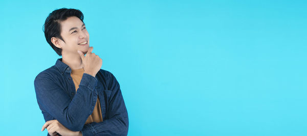 Teenage girl looking away against blue background