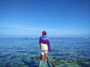 Rear view of man standing in sea against clear sky