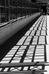 Shadow of person walking on bridge in city