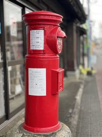 Red mailbox on street against building in city