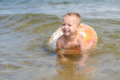 Smiling boy with inflatable ring swimming in sea