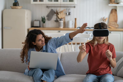 Young woman using laptop while sitting on sofa at home