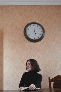 Young woman smiling against wall