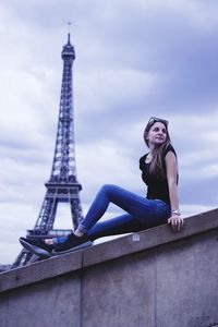 Full length of young woman with tower against cloudy sky