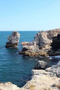 Scenic view of rocks in sea against clear sky