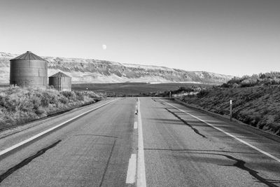 Road leading towards mountain against clear sky