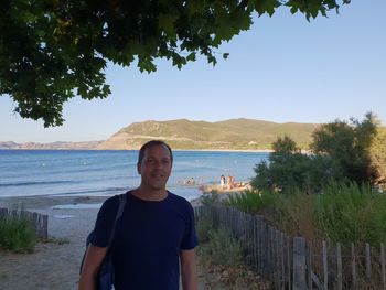 Young man standing on beach against sky