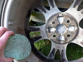 Cropped image of person hand cleaning car wheel