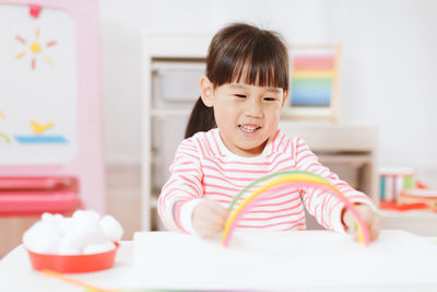 Young girl making rainbow craft using pipe cleaner at home