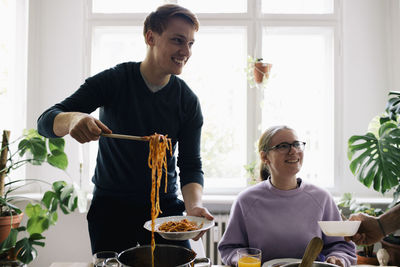 Smiling man removing spaghetti in plate at home