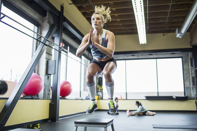 Woman jumping over stool in gym