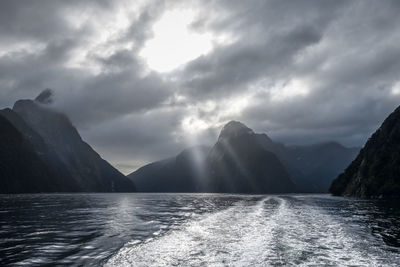 Scenic view of sea by mountains against sky