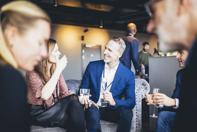 Smiling business people talking while sitting in office