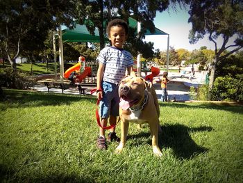 Portrait of happy boy with dog on grass